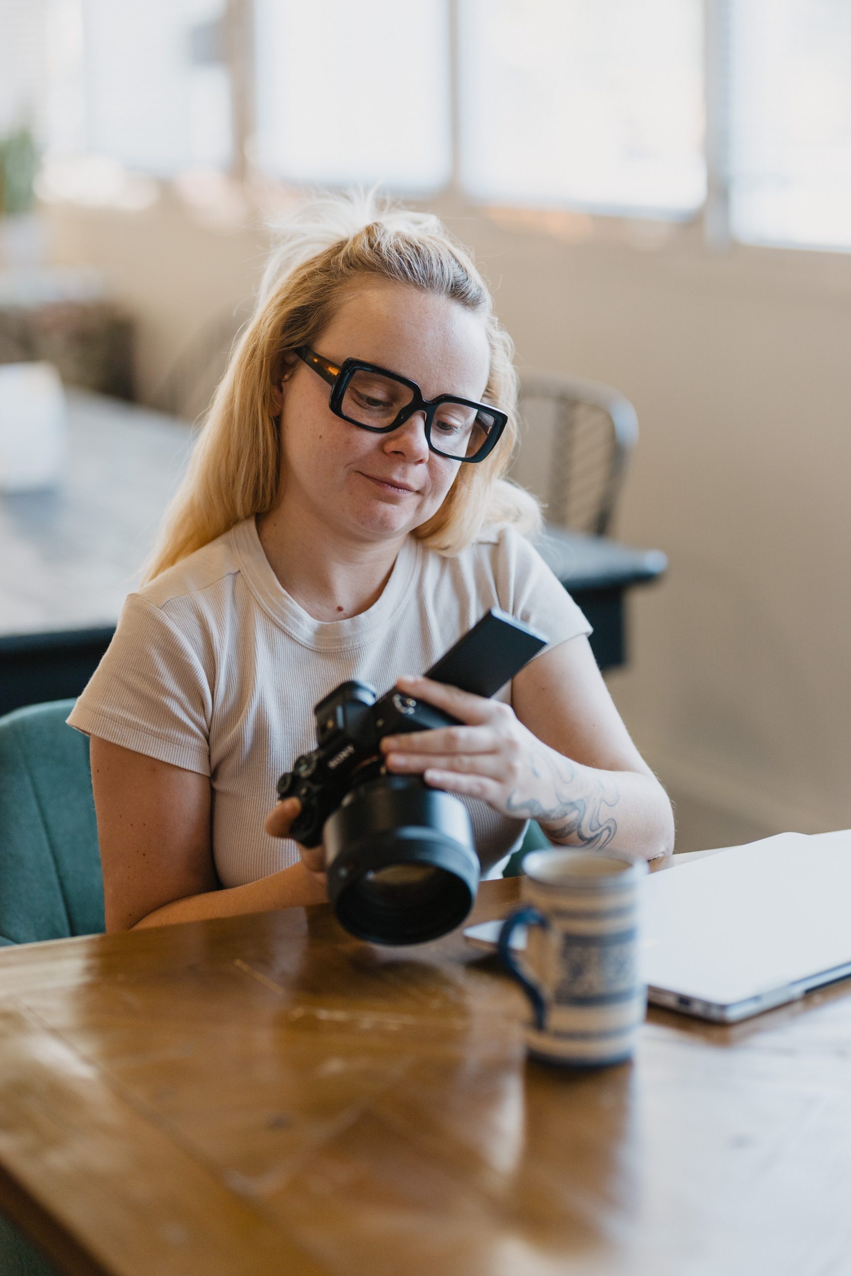 Photo d'une photographe assise à un bureau entrain de regarder son appareil photo